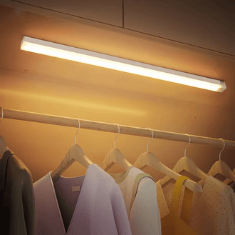 LED counter night light illuminating clothes in a wardrobe, showcasing its sleek design and warm glow.